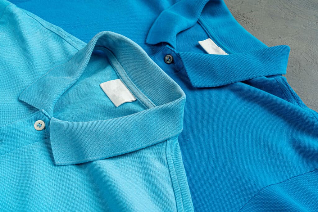 一件深藍色的高品質 polo 衫平鋪在桌上,旁邊放著訂製用的捲尺與布樣,展現專業質感。